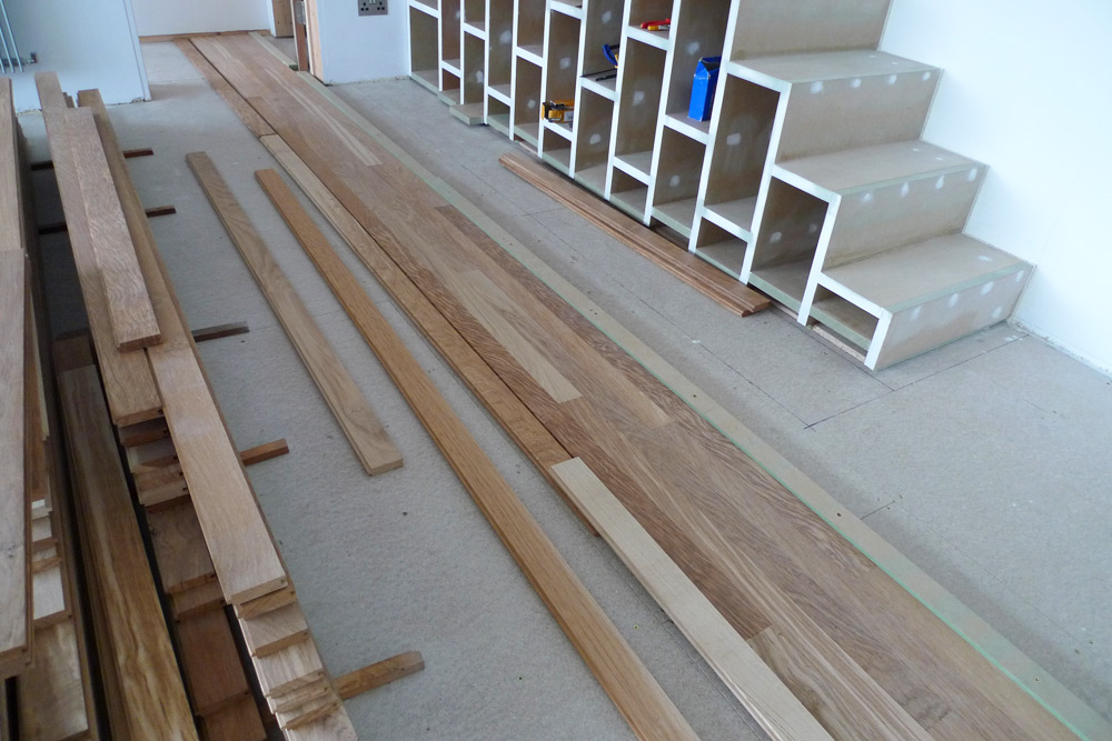 Rebuild - Laying of English Tiger Brown Oak flooring on lower floor with storage stairs in background
